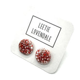 A pair of textured round stud earrings in a speckled hot pink and white, displayed on a white card with the text &