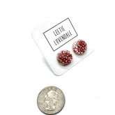 A pair of textured round stud earrings in a speckled hot pink and white, displayed on a white card with the text &