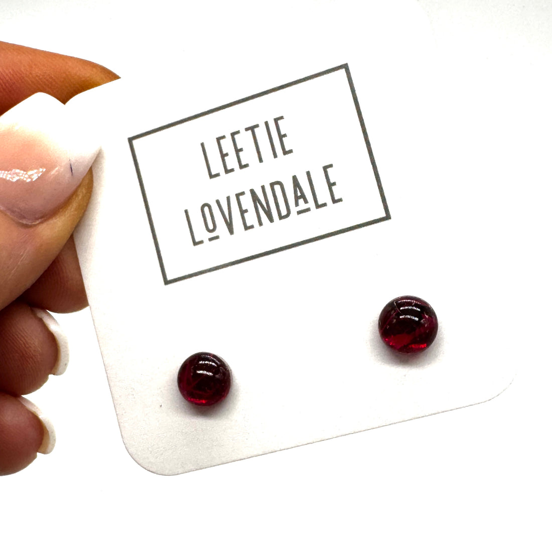 A hand holding a white display card with the brand name &