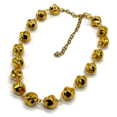 A gold-toned beaded necklace featuring textured, polished, twisted round  beads connected by delicate chain links, with an adjustable clasp, shown on a plain white background.