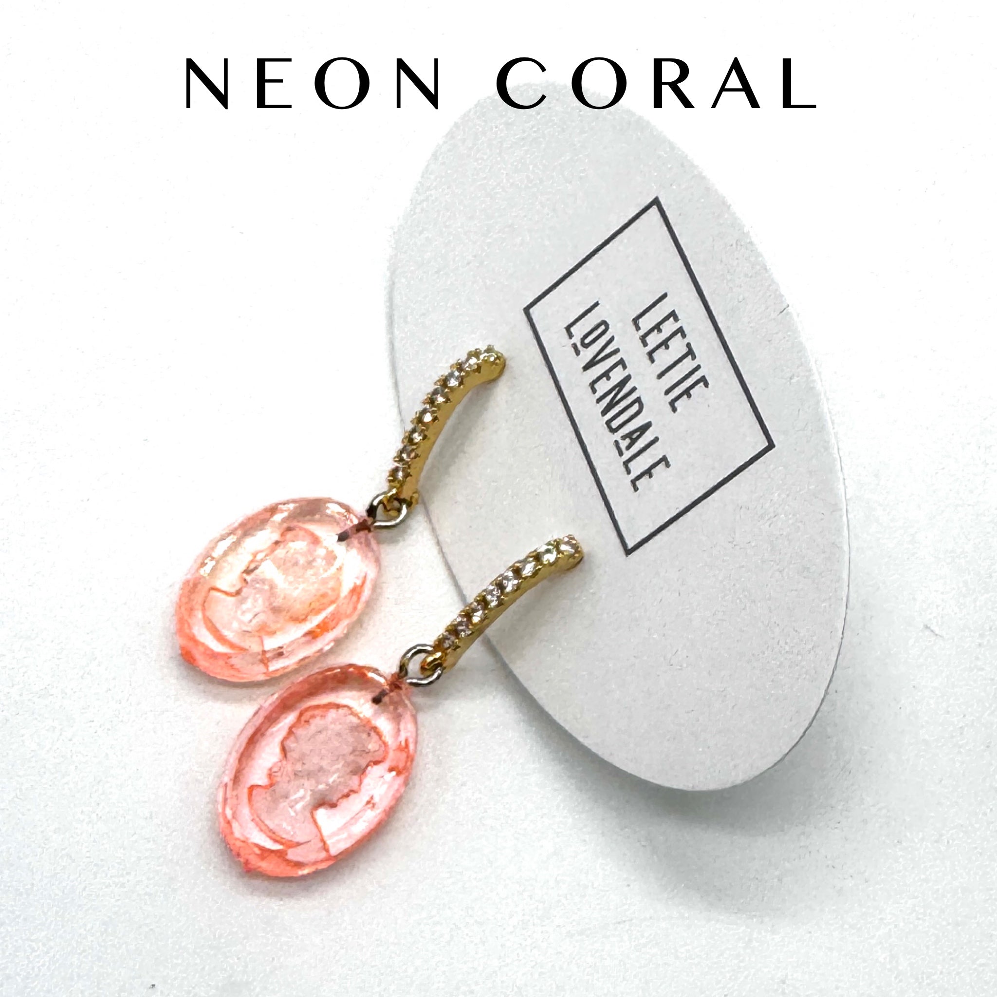 Neon coral earrings on a white card with &