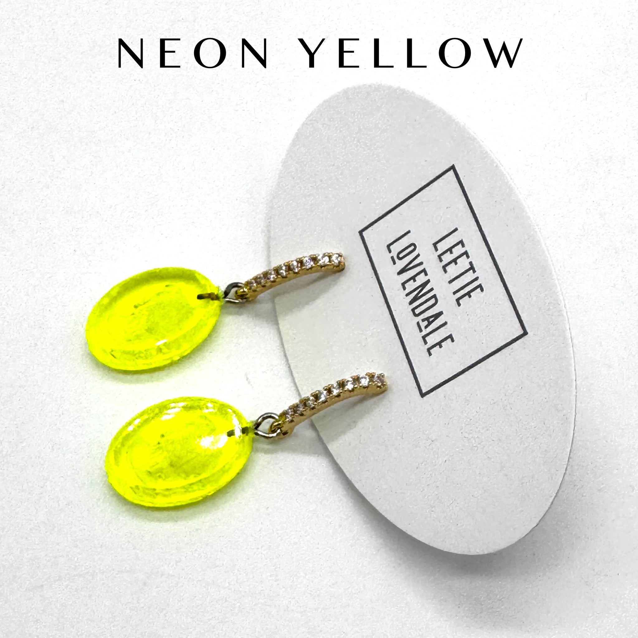 Neon yellow earrings on a white card with &