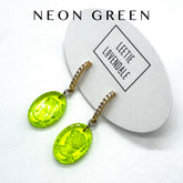 Neon green earrings on a white card with &