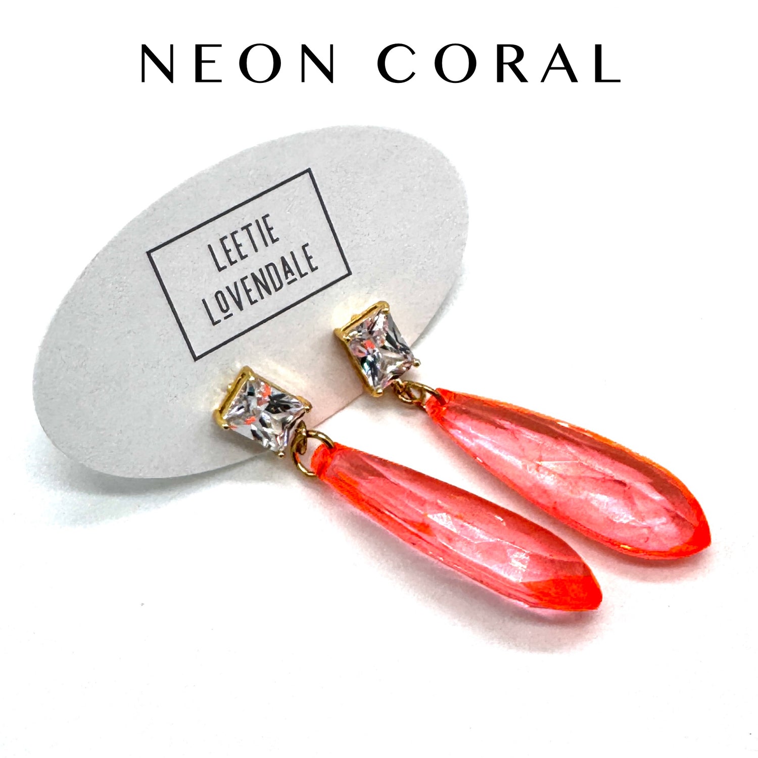 Neon coral earrings with crystal accents on a white background, featuring the brand &