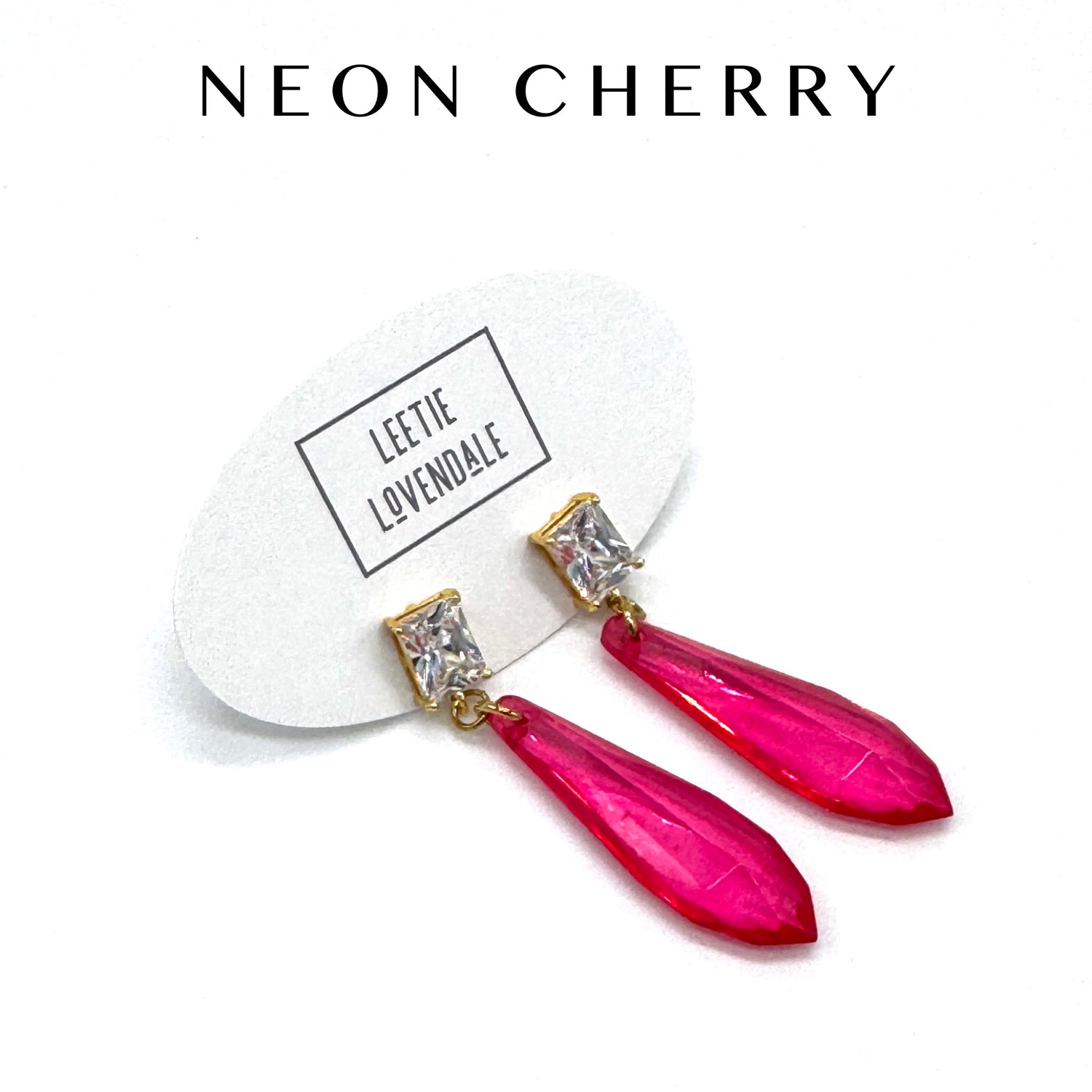 Pink earrings with gold accents on a white card with &