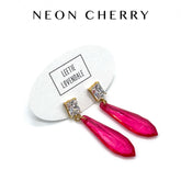 Pink earrings with gold accents on a white card with &
