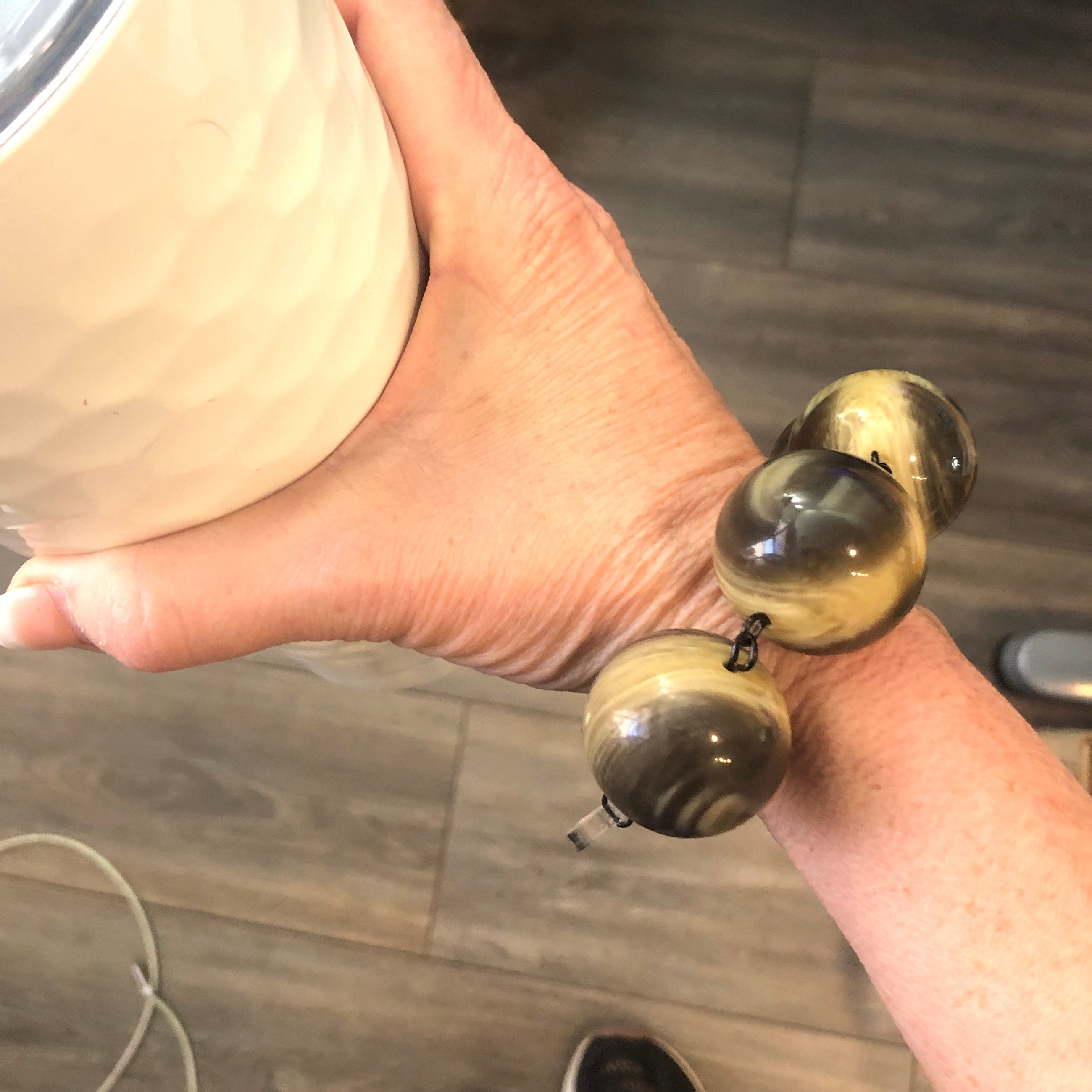 brown beaded bracelet on a hand holding a cup