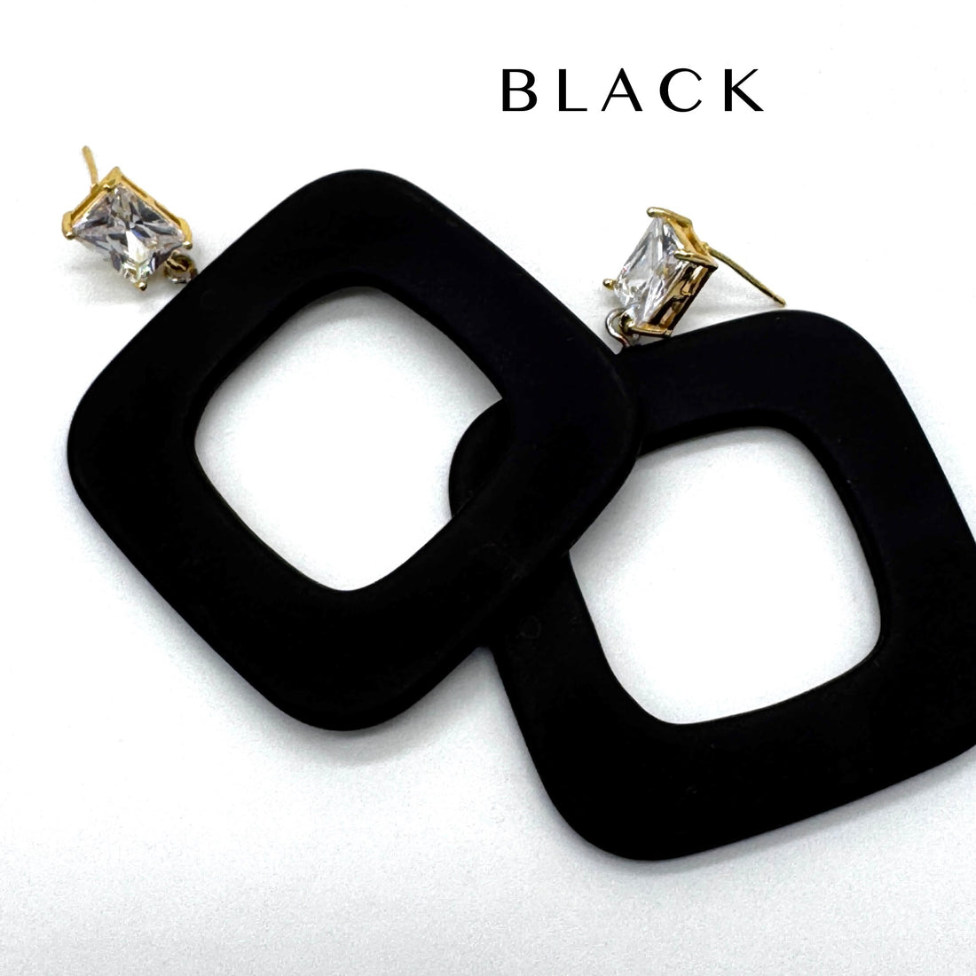 Black square drop earrings with gold-tone posts and clear rectangular crystals, shown on a white background with the word &