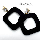 Black square drop earrings with gold-tone posts and clear rectangular crystals, shown on a white background with the word &