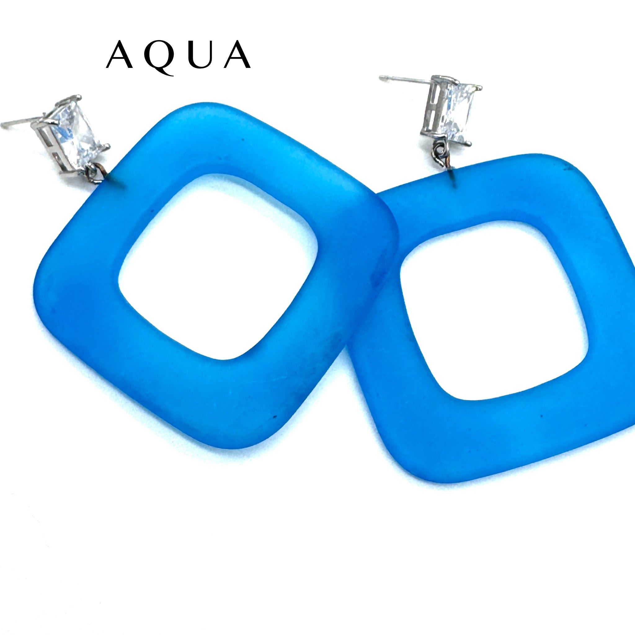 A pair of large square-shaped aqua blue lucite earrings with clear rectangular rhinestones on silver posts, shown against a plain white background with the brand name &