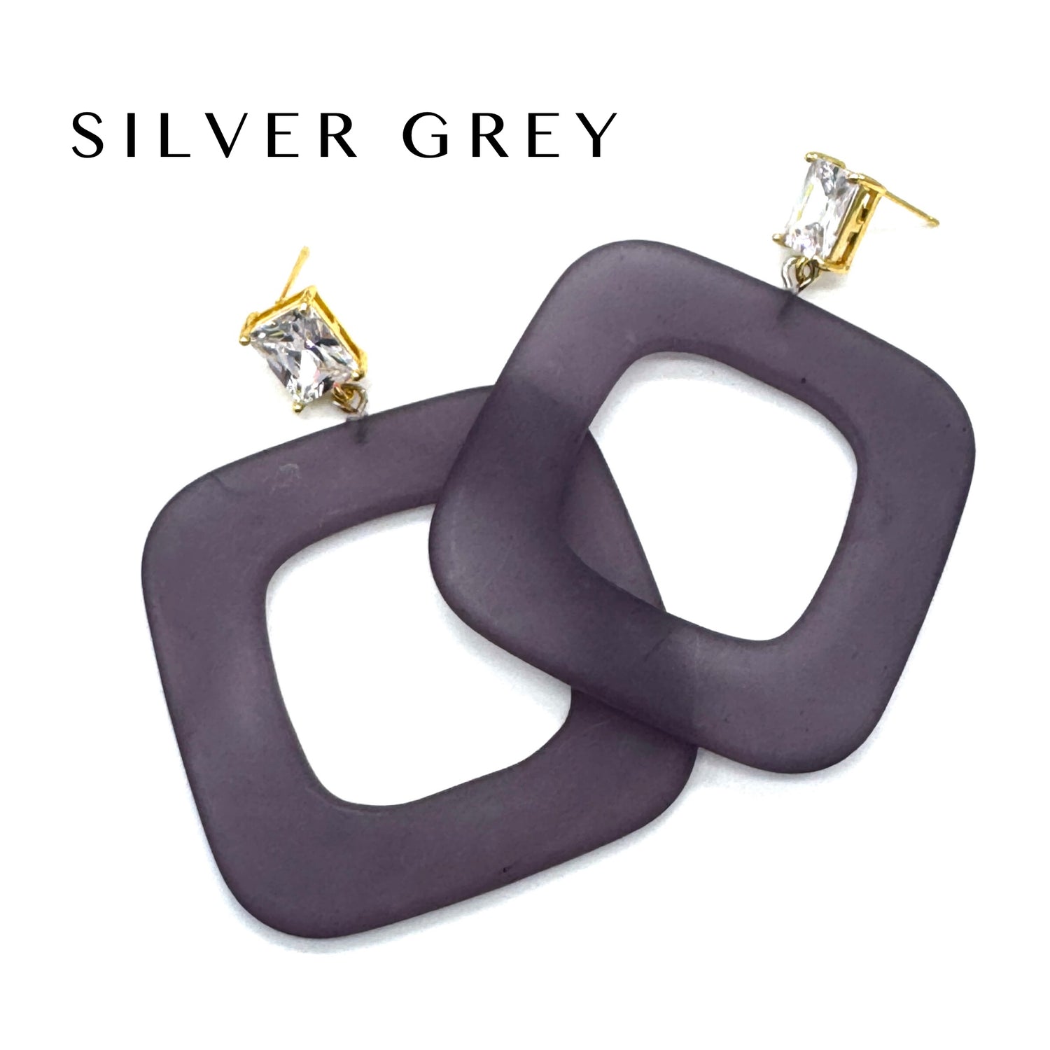 Square open-frame dangle earrings in a dark greyish-purple color with gold-tone posts and clear rhinestones, shown on a white background with the text &