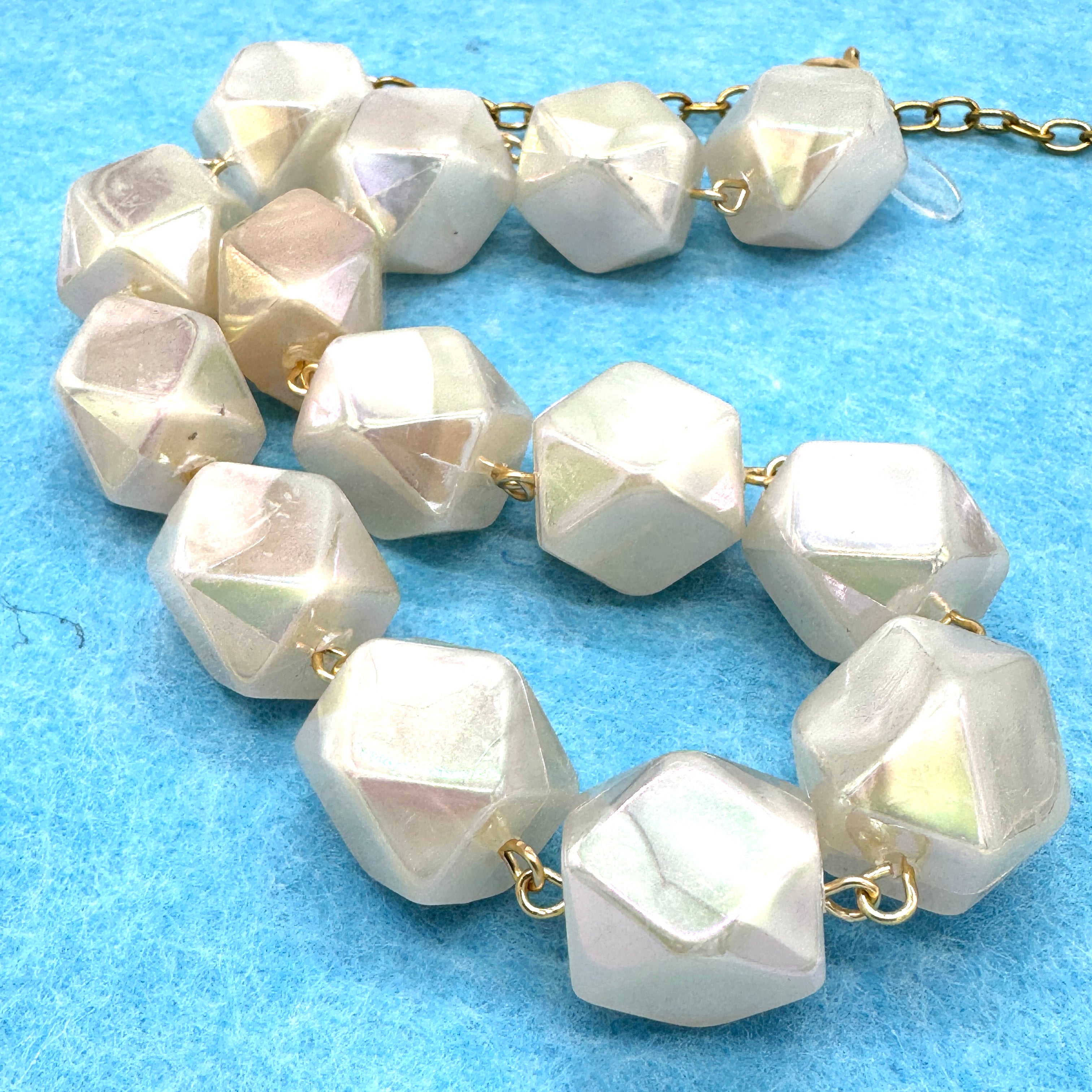 Necklace with faceted white beads on a blue background