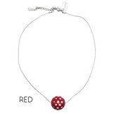 Necklace with a red and white polka dot pendant on a white background