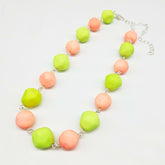 Peach and lime green beaded necklace on a white background.