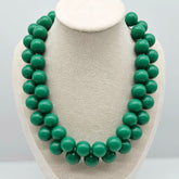 Opaque green beaded necklace on a bust.
