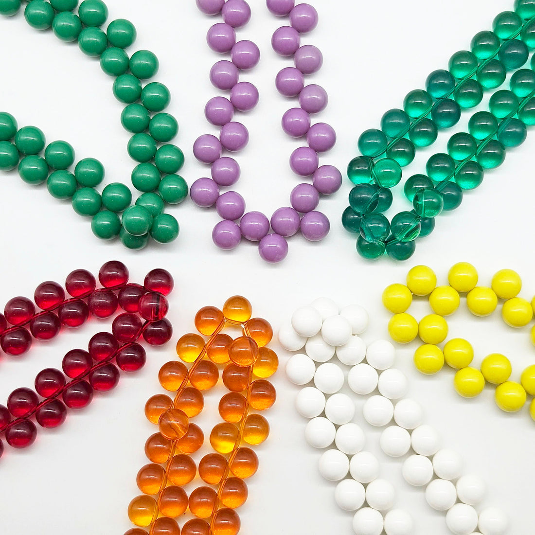 Multiple colorful beaded necklaces laid out in a circle on a white background.