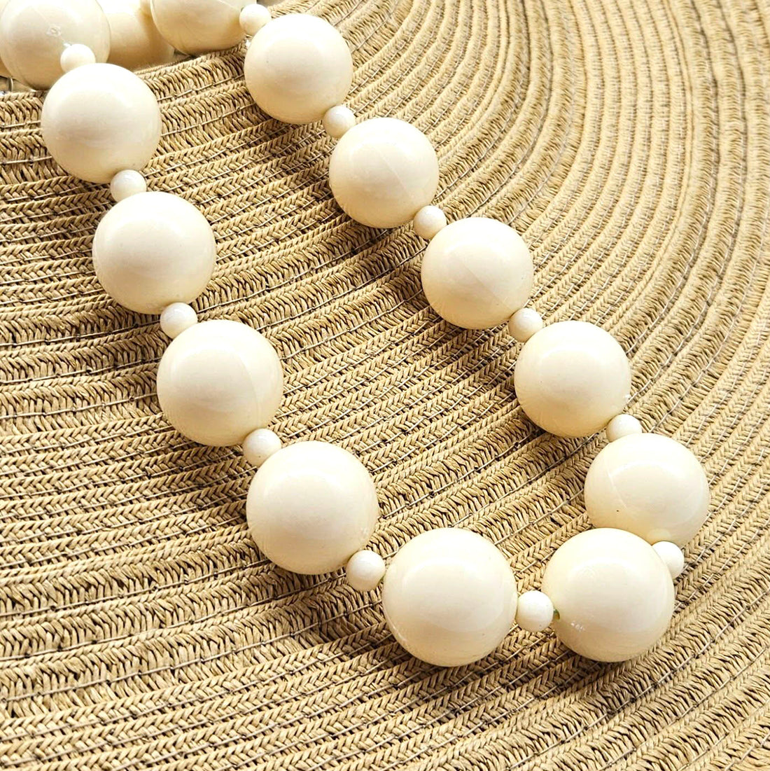 White beaded necklace on a textured beige surface