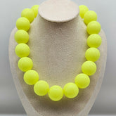 Neon yellow bead necklace on a beige jewelry display
