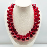 Red cluster beaded necklace on a bust.
