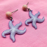 Starfish-shaped earrings on a pink background